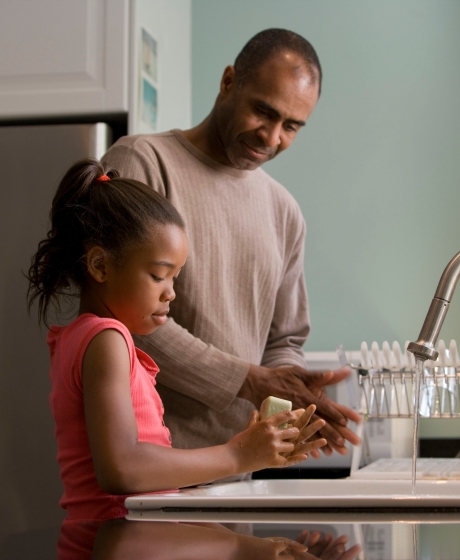 daughter washing hands at kitchen sink with father