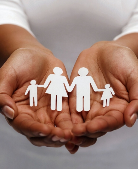 Hands holding paper cut out family