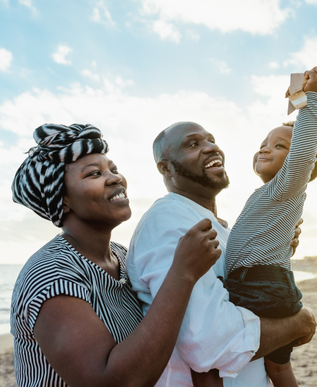 African couple with their young child at the beach.