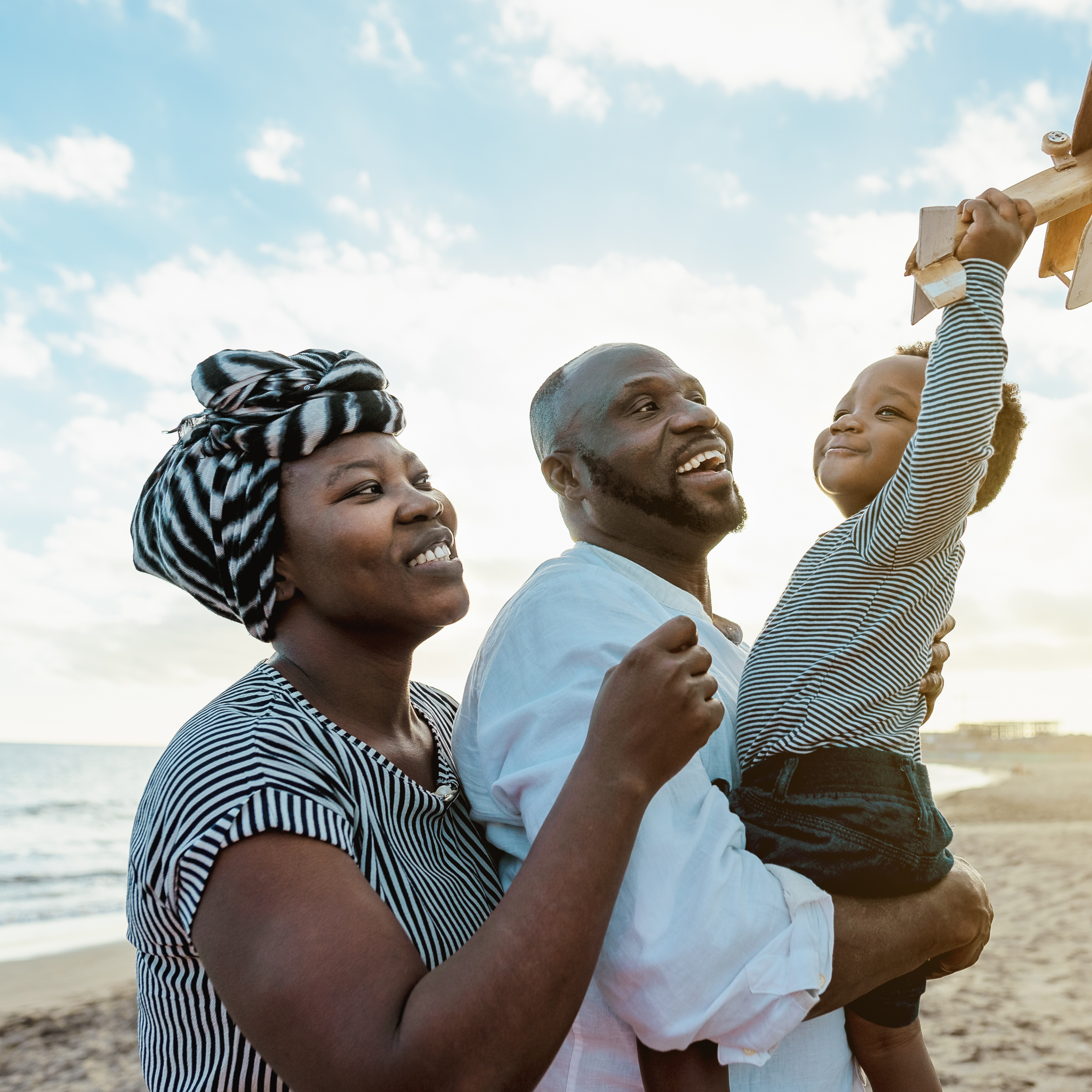 African couple with their young child at the beach.