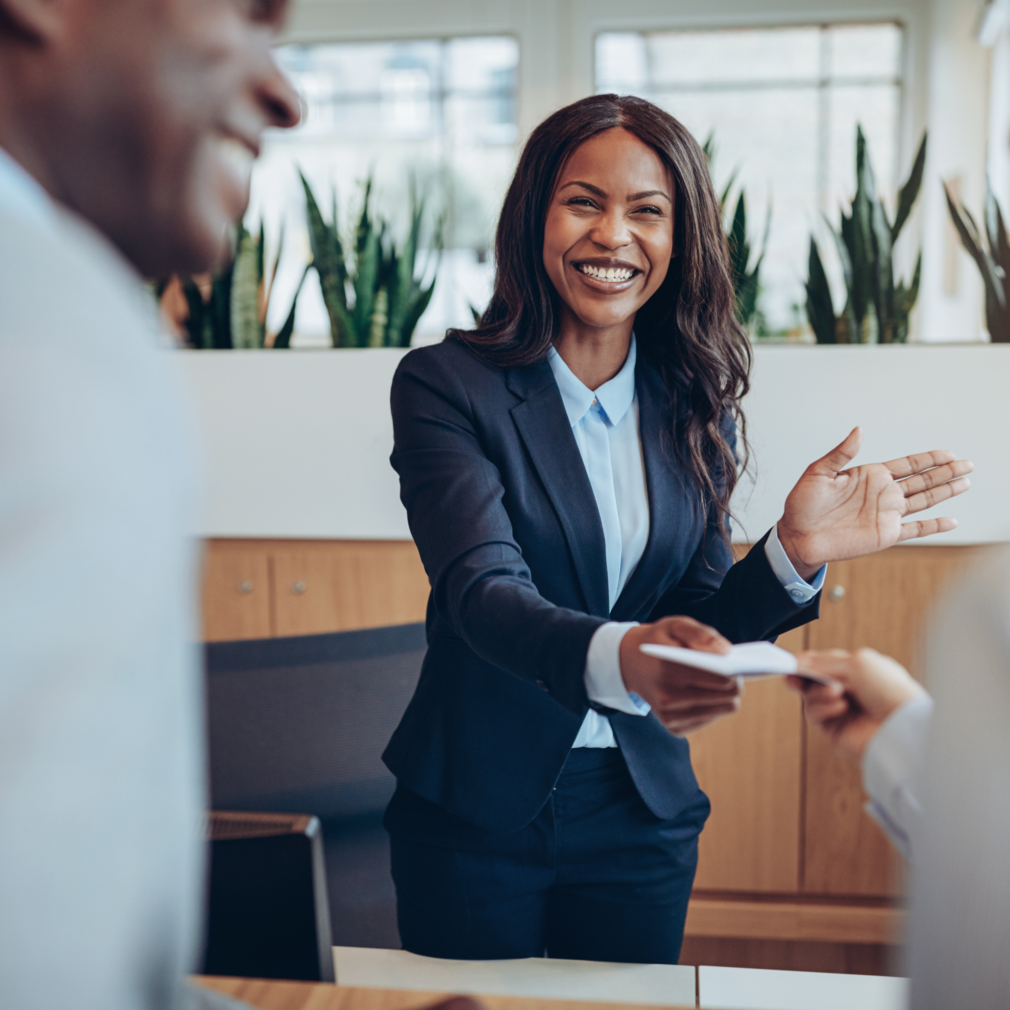 African business woman smiles as she hands over a document.