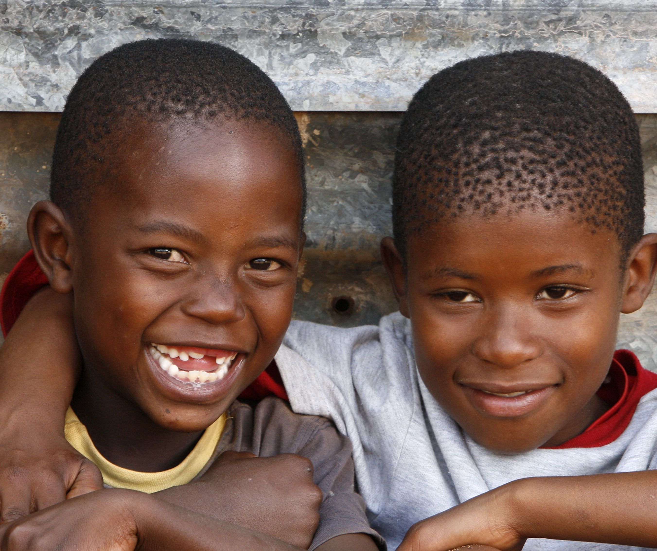 Two kids laughing and arms around their shoulders