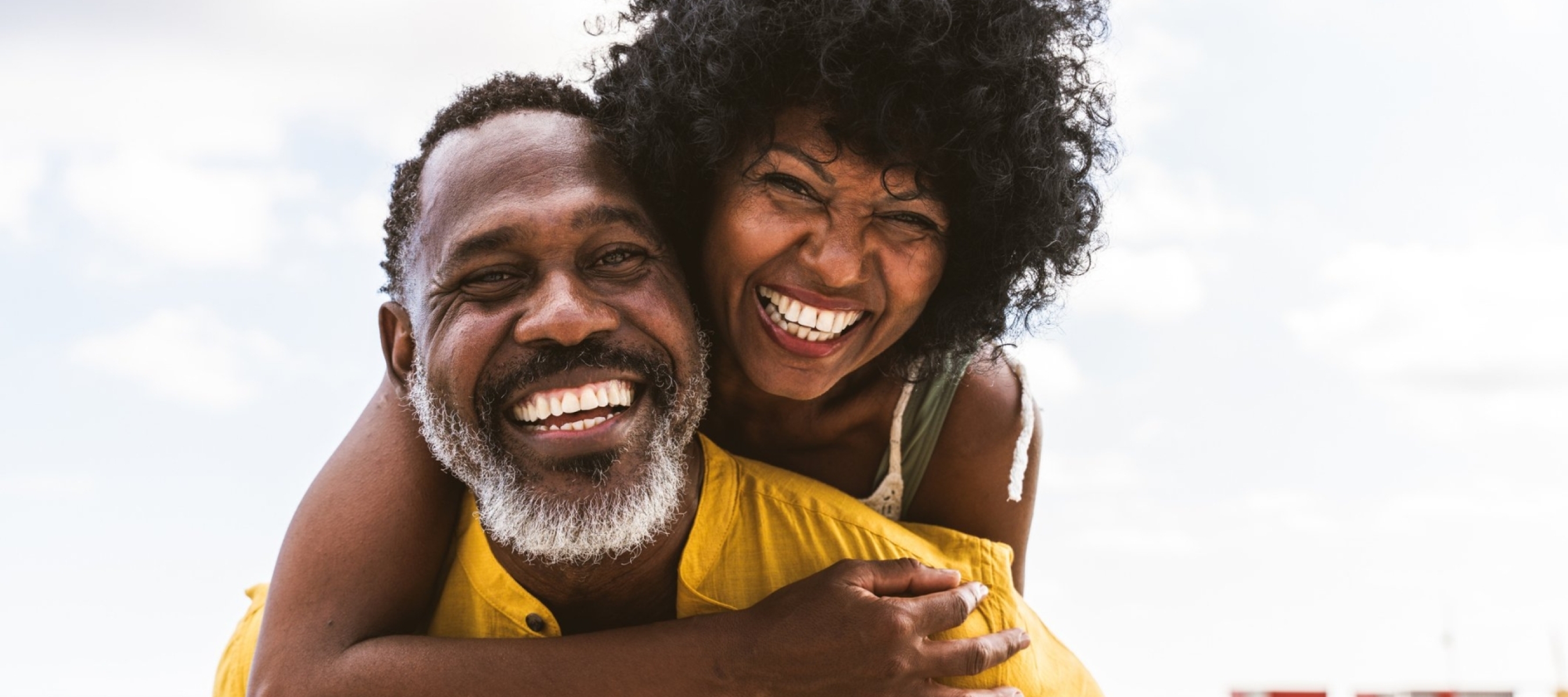 African couple smiling with wife on husband's shoulders